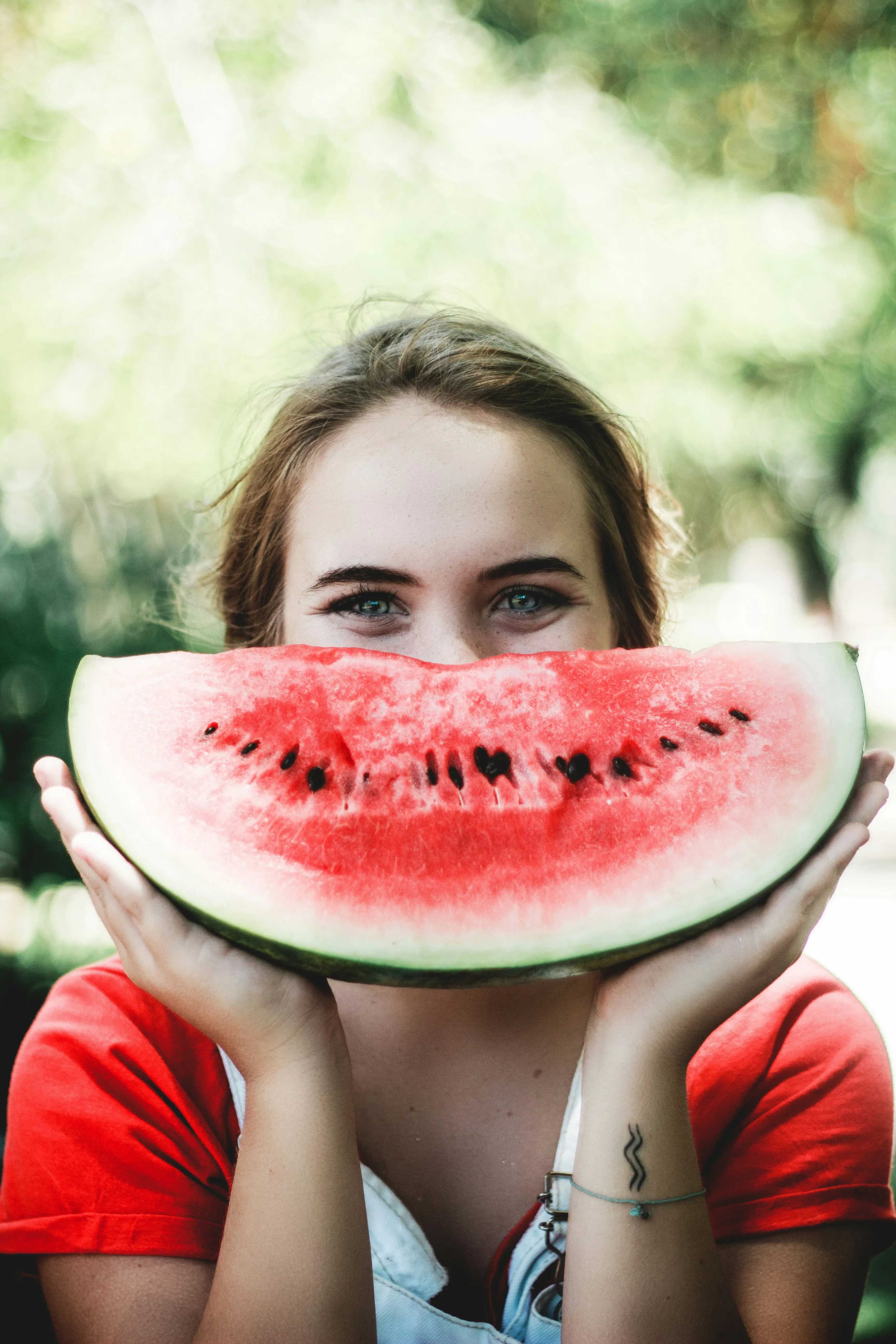 Woman playfully posing with a watermelon slice smile