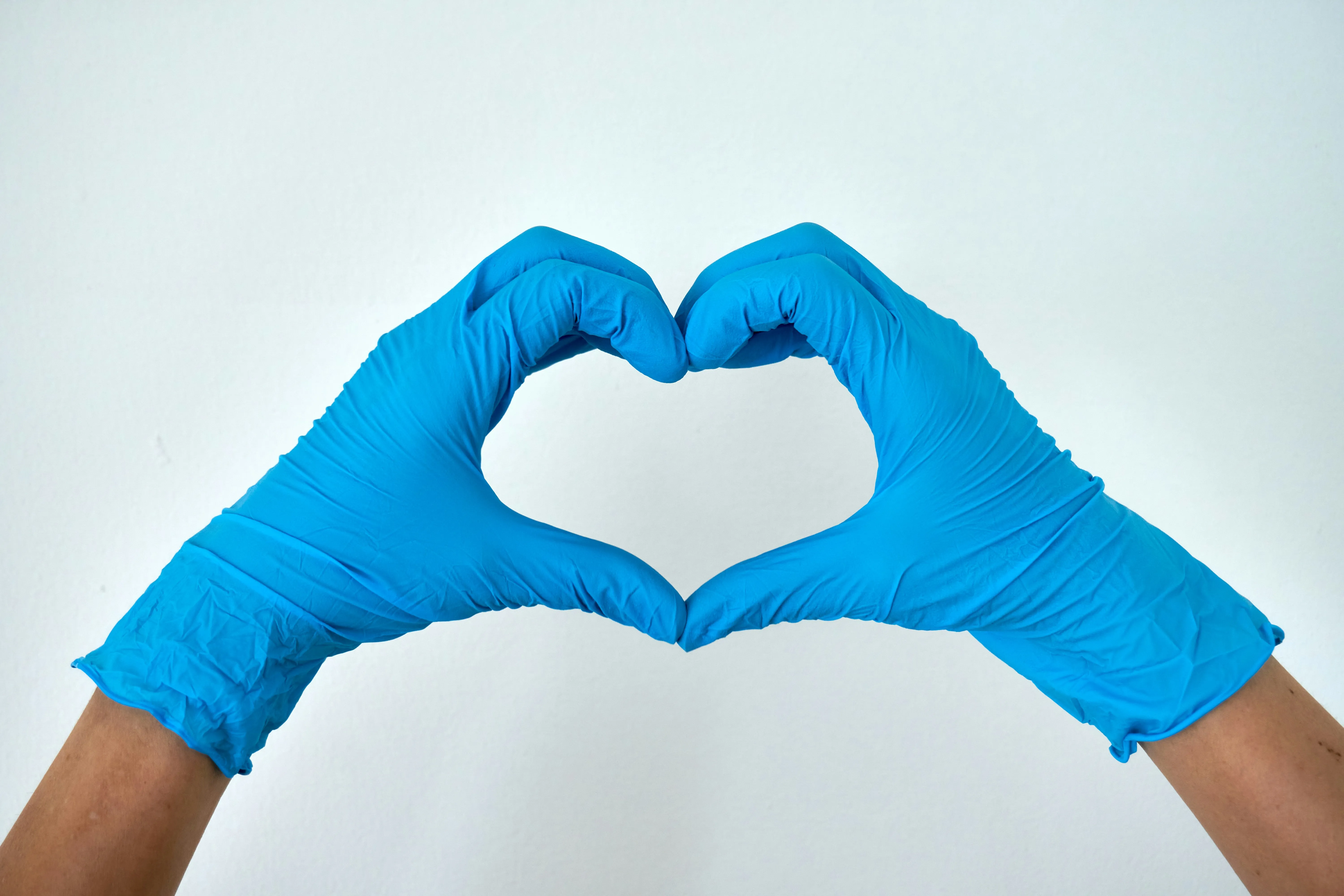 Medical professional making a heart shape with gloved hands